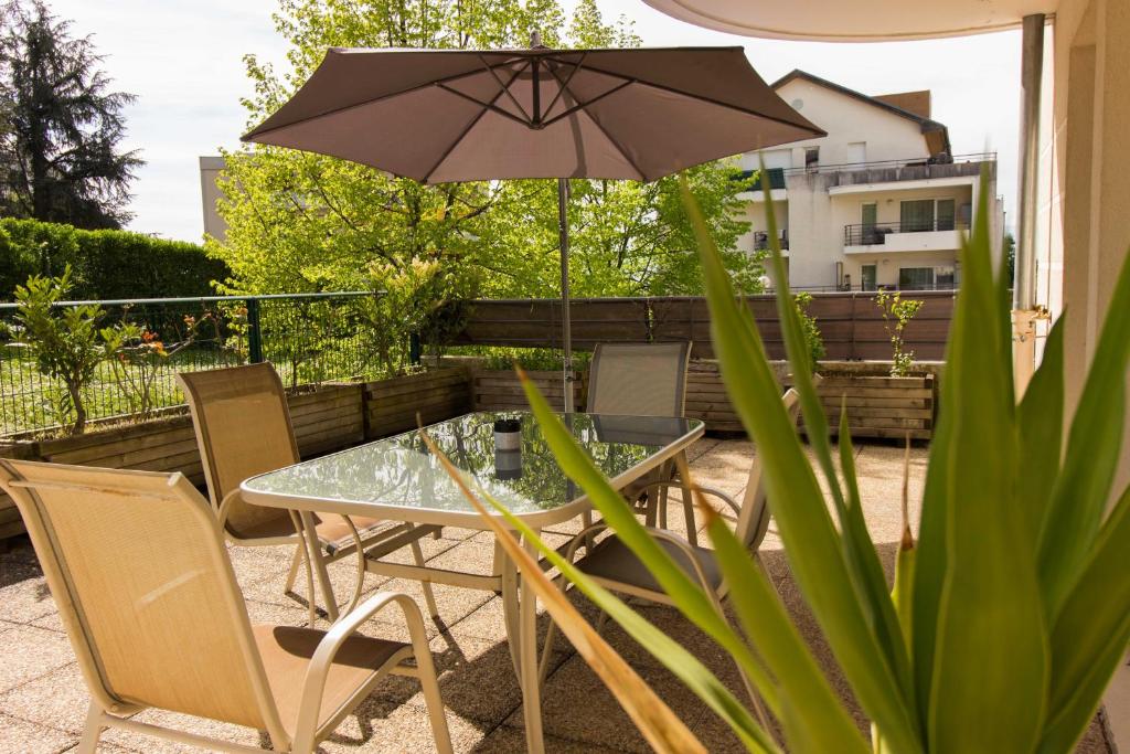 une table et des chaises avec un parasol sur une terrasse dans l'établissement Logement avec grande terrasse., à Vétraz-Monthoux
