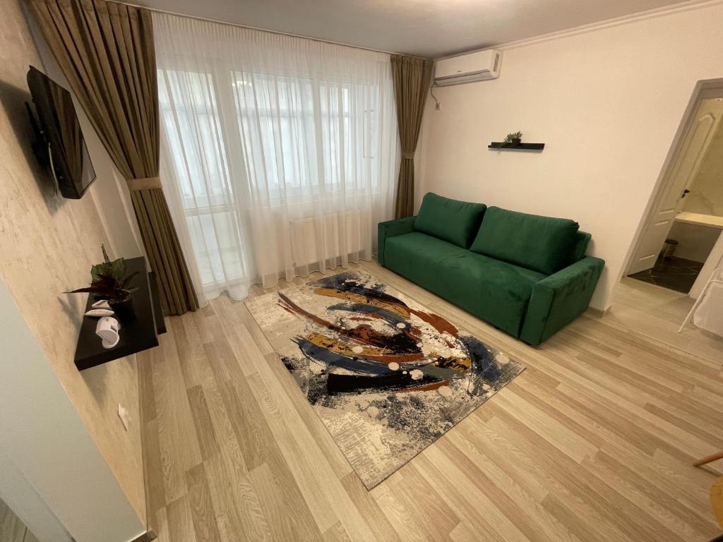 een woonkamer met een groene bank en een tapijt bij Apartament Central in Onești