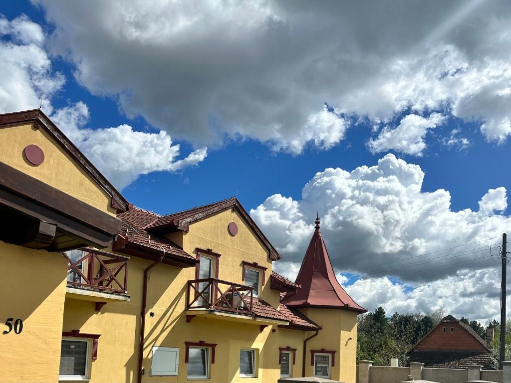 a yellow building with a sky with clouds at Aqua terme Palic in Palić