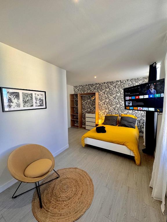 - une chambre avec un lit jaune et une télévision dans l'établissement Le Victor Hugo & son jardin, à Montluçon