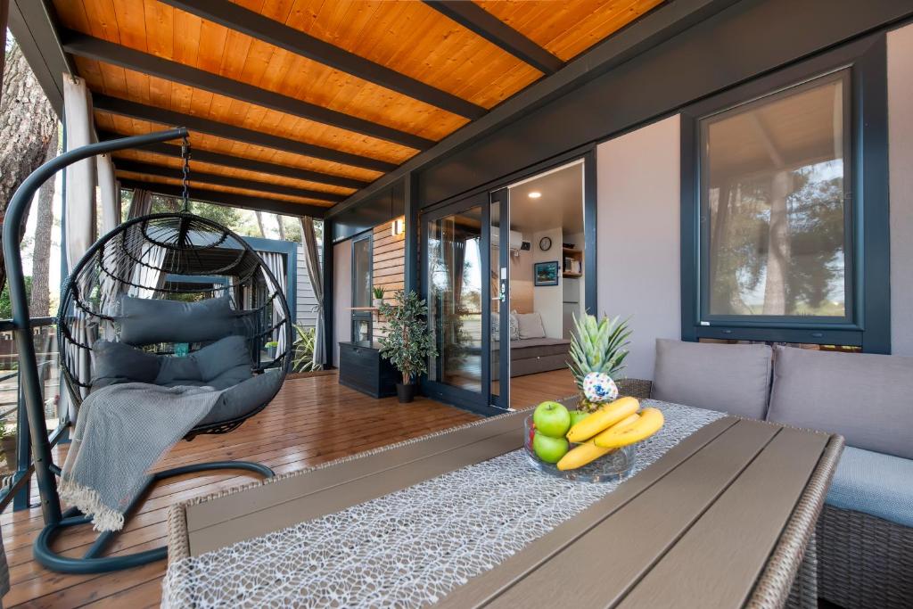 a porch with a bench with a bowl of fruit on it at Mobile home MAŠA 163, camp Porton Biondi in Rovinj