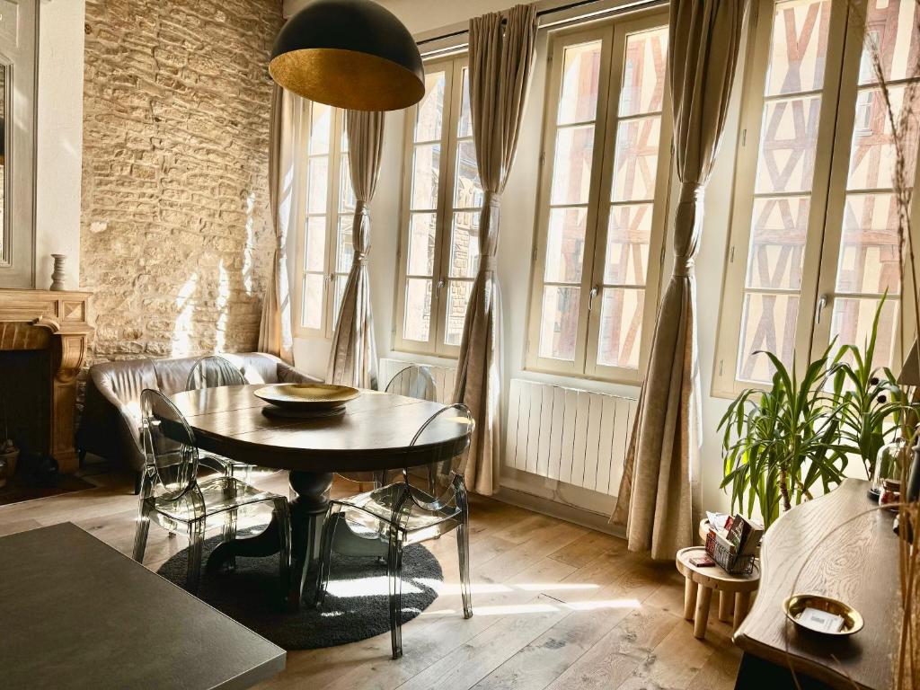 a living room with a table and some windows at Le Lion des Ducs : centre historique de Dijon in Dijon