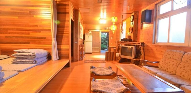una habitación con sofá y TV en una cabaña en La La Mountain Taohuayuan Farm en Hualing