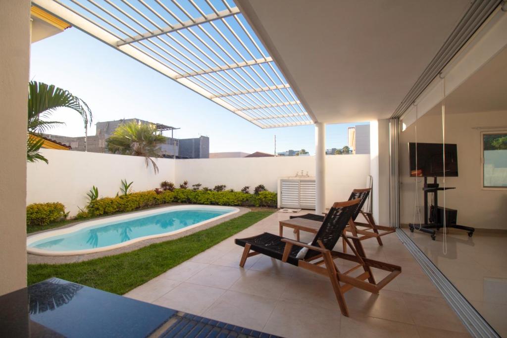 um pátio com uma piscina, uma cadeira e uma televisão em Pacific Shores Retreat & Getaway em Nuevo Vallarta 