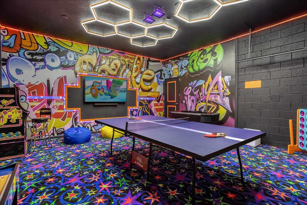 uma mesa de pingue-pongue numa sala com graffiti em 12BR Family Home w Pool and Hot tub em Kissimmee