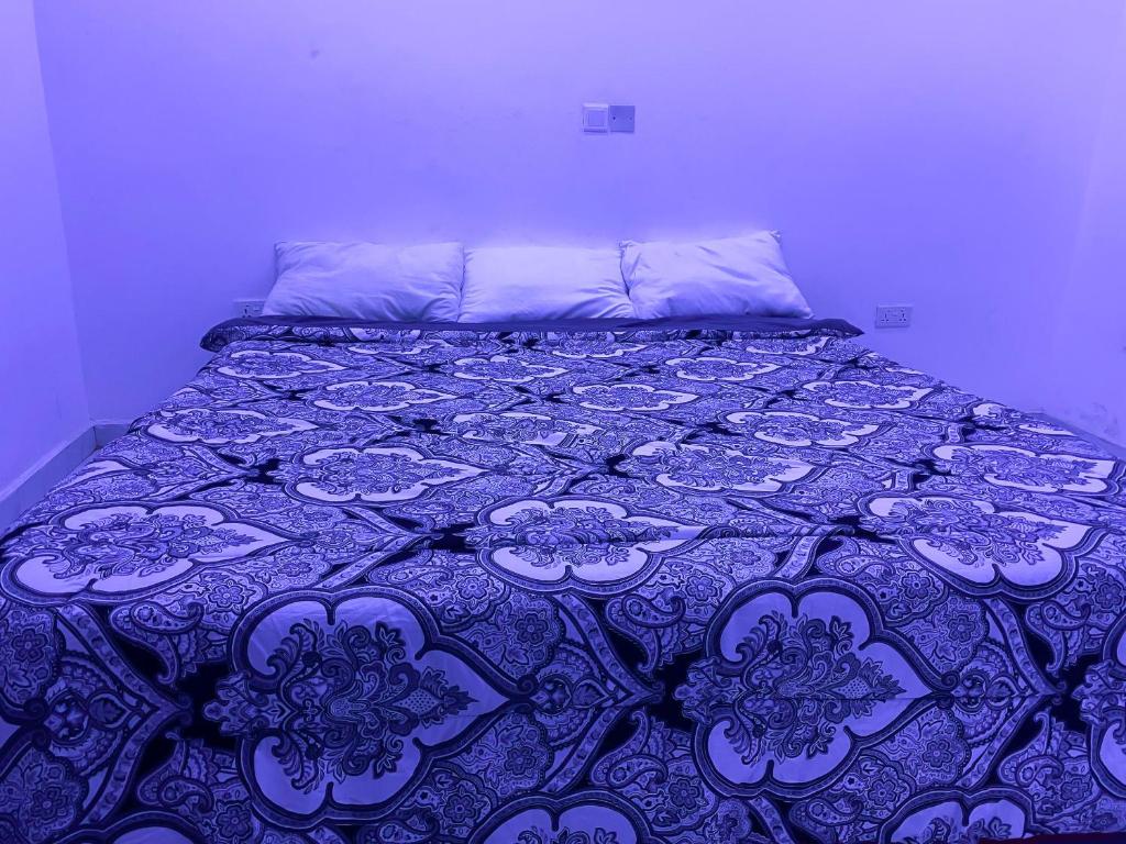 a bed with a purple and white bedspread on it at Irish Apartment in Kasoa