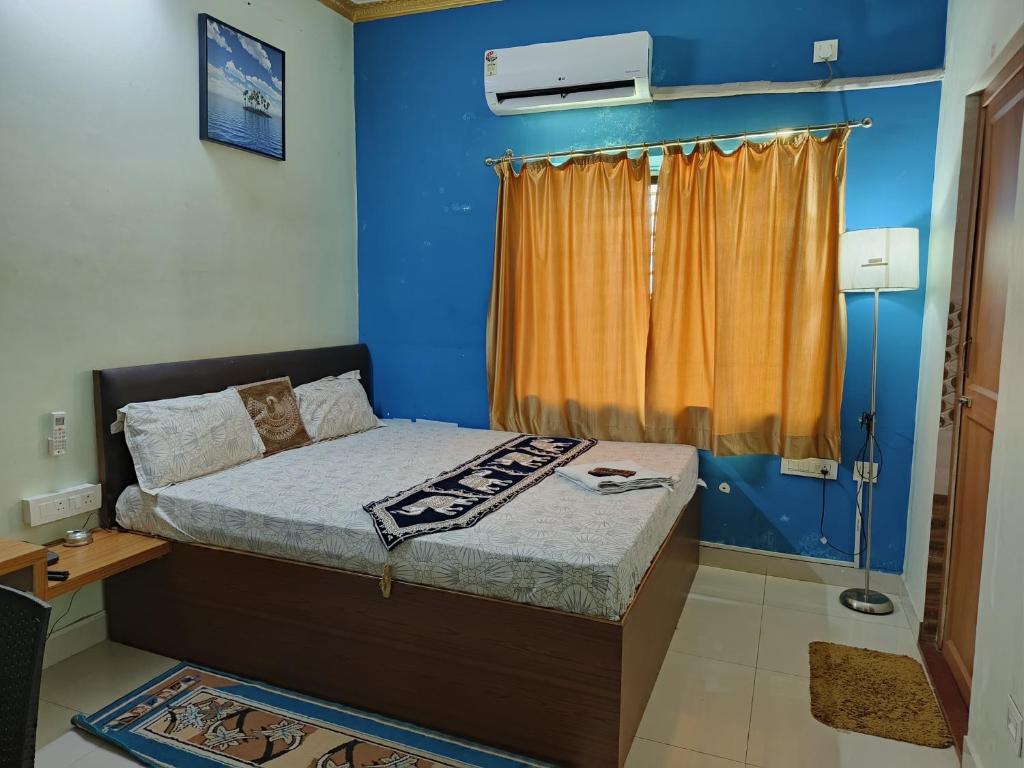 a bedroom with a bed with blue walls and a window at Hotel GD Stay Inn Near Mahura Chhak in Bhubaneshwar