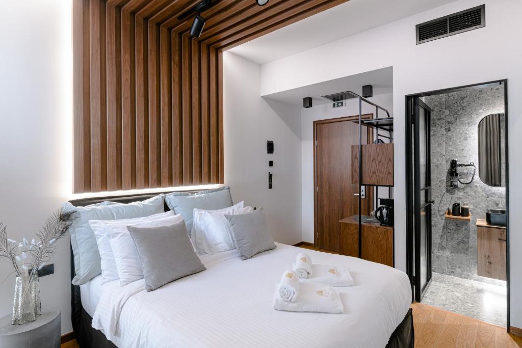 una camera da letto con un letto bianco e asciugamani di Snob Athens ad Atene