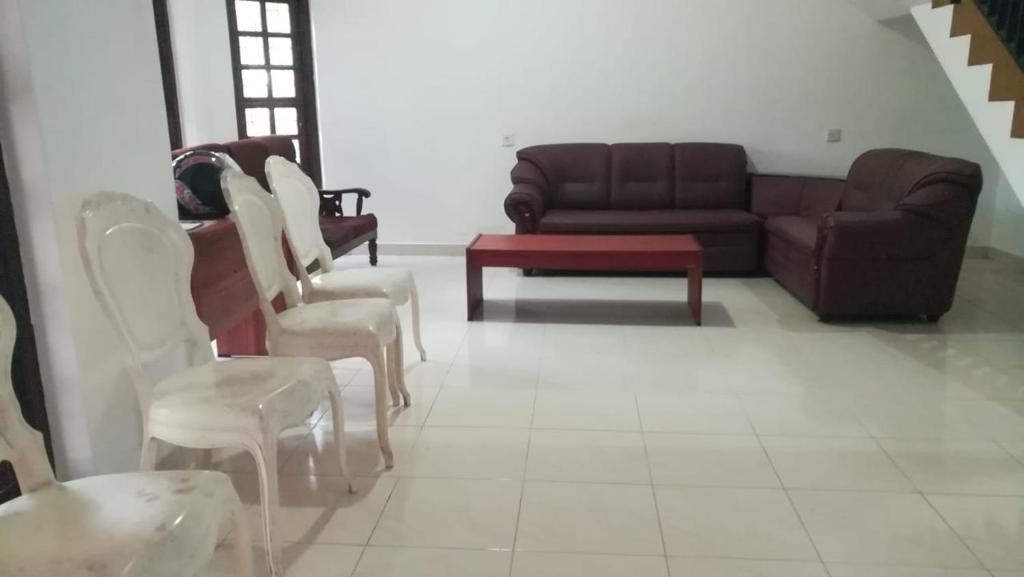 ein Wohnzimmer mit einem Sofa und weißen Stühlen in der Unterkunft Wessagiri resort in Medawachchiya