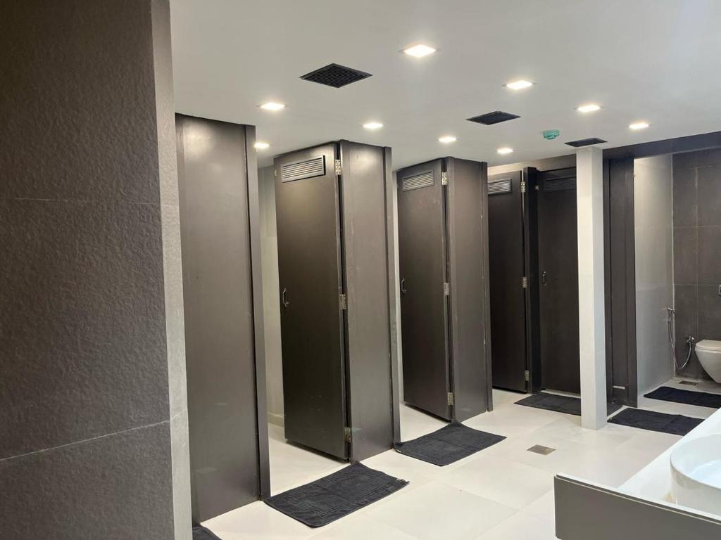 a row of stalls in a bathroom with a toilet at OSTELO Mumbai Airport Hostel in Mumbai