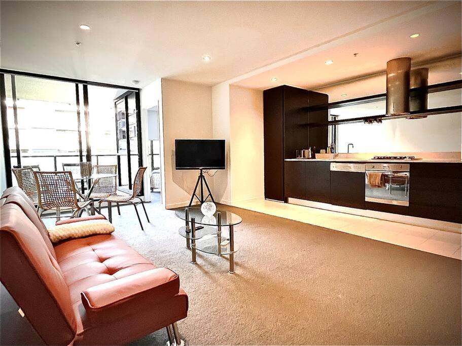 a living room with a couch and a tv and a kitchen at Abbotsford Apartment: Yarra River & CBD nearby in Melbourne