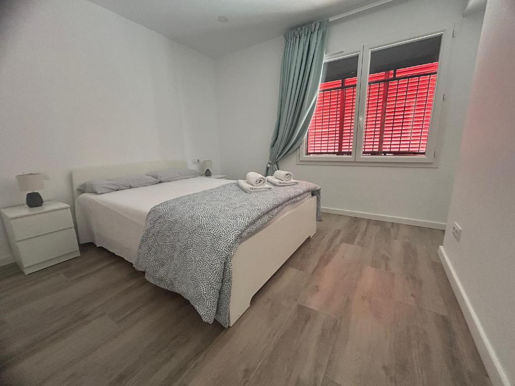 a white bedroom with a bed and two windows at Canyelles BBQ Apartment in Lloret de Mar