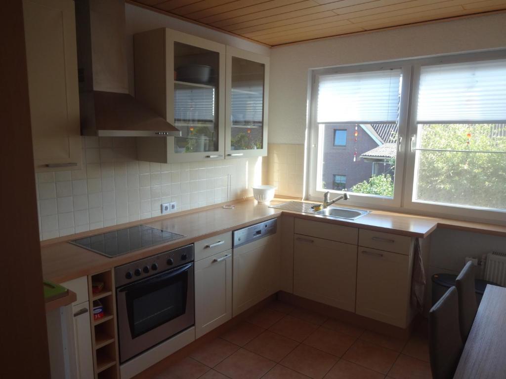 uma cozinha com armários brancos, um lavatório e duas janelas em Ferienwohnung auf dem Lande em Loxstedt