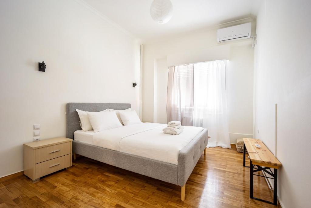 a white bedroom with a bed and a wooden floor at Acropolis Delux 1st FLR Aprt up 4 guests by LODGESPOT in Athens