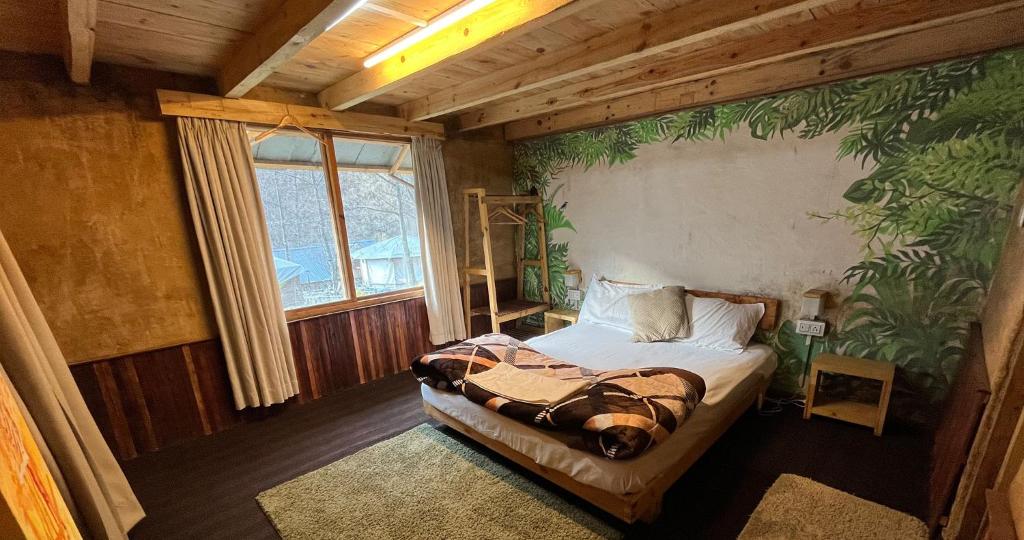 a bedroom with a bed with a plant mural on the wall at Aloha Riverside in Kasol