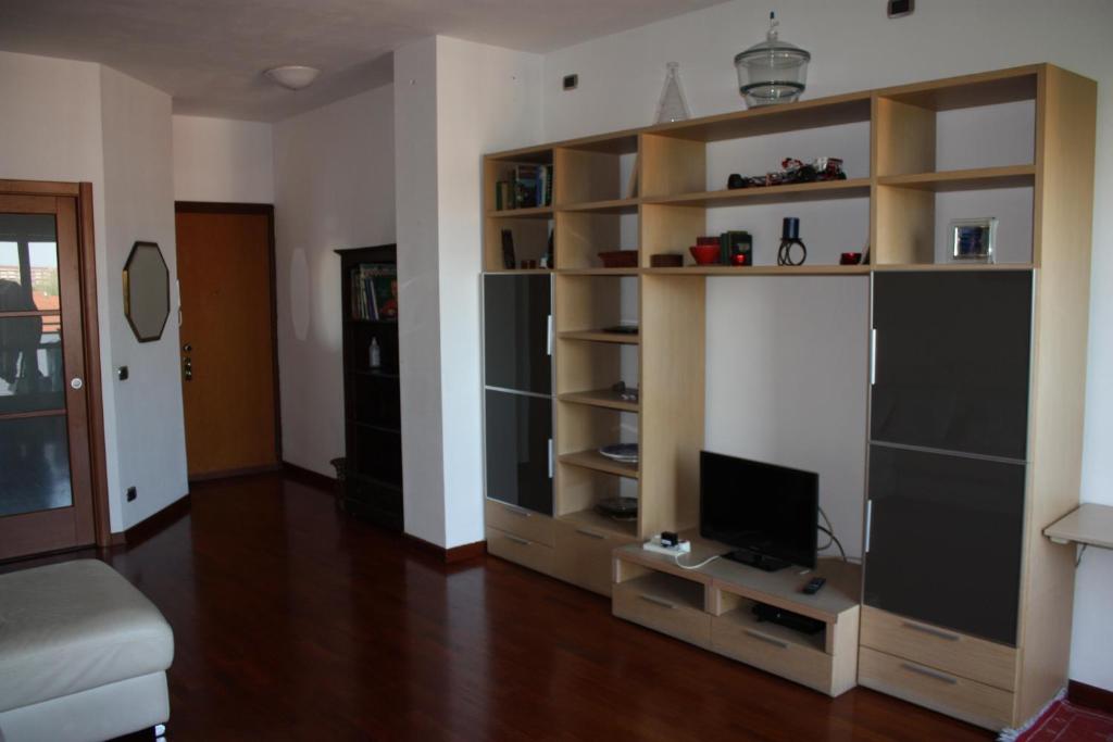 a living room with a large book shelf with a television at Elegante appartamento trilocale in Milan