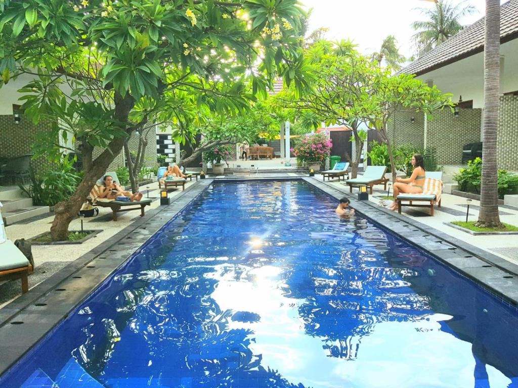 una piscina de agua azul y personas en un complejo en Villa Pine Tree, en Gili Trawangan