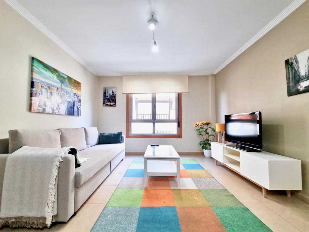 a living room with a couch and a tv at Apartamento en la playa! in Sanxenxo