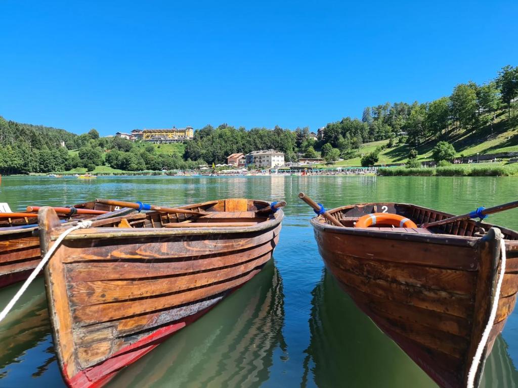 two wooden boats are docked on a lake at Grand Hotel Astoria in Lavarone