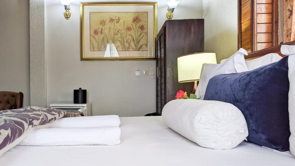 1 dormitorio con 1 cama con sábanas blancas y almohadas azules en Savoy Palmz, en Limbe