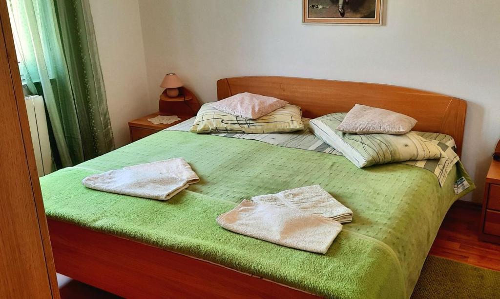 uma cama verde com duas toalhas em cima em Apartman Nada em Cres