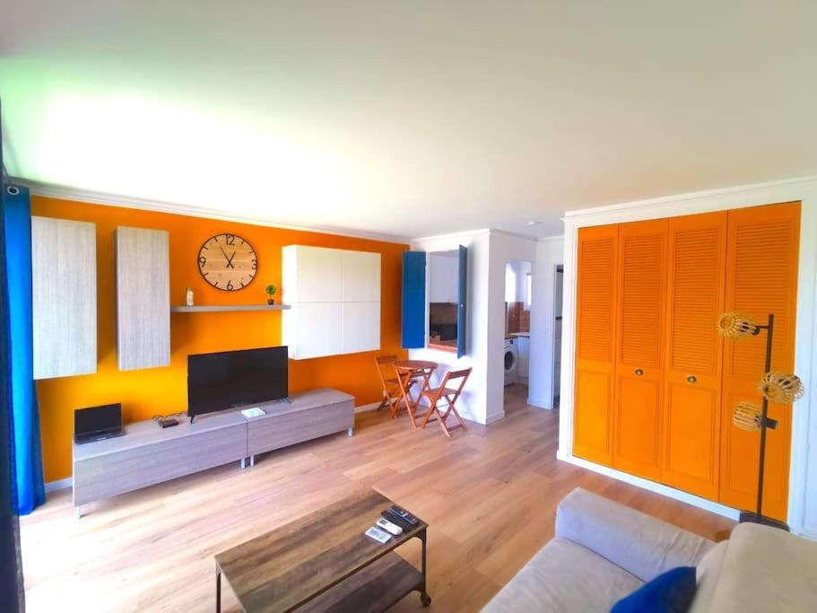 un salon avec un canapé et une horloge au mur dans l'établissement Studio terrasse - 2 min de la mer, à Saint-Laurent-du-Var