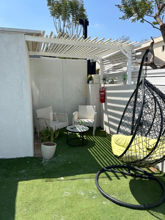 eine Terrasse mit einer Schaukel, einem Tisch und Stühlen in der Unterkunft Shalva in Aschkelon