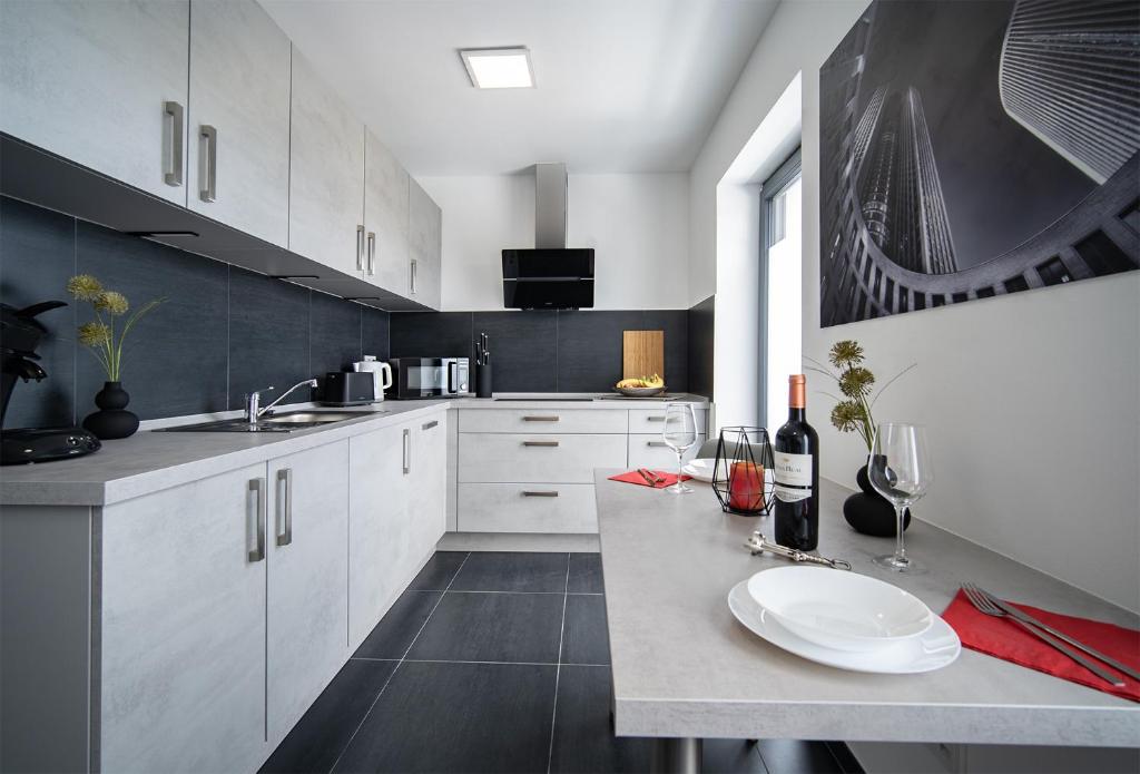 a kitchen with white cabinets and a table with wine glasses at Blauer Stein Apartments WH4 in Pulheim