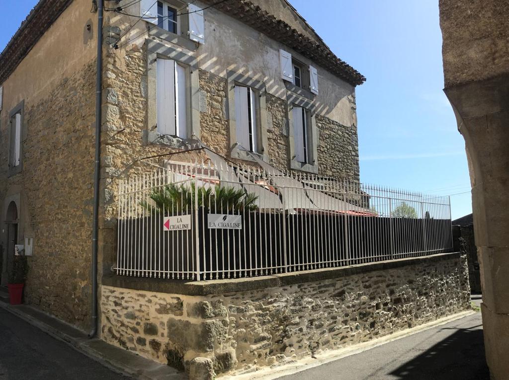 a building with a fence on the side of it at La Cigaline in Laure-Minervois