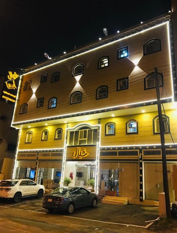 un grand bâtiment jaune avec des voitures garées devant lui dans l'établissement خيال ابها للوحدات السكنية, à Abha