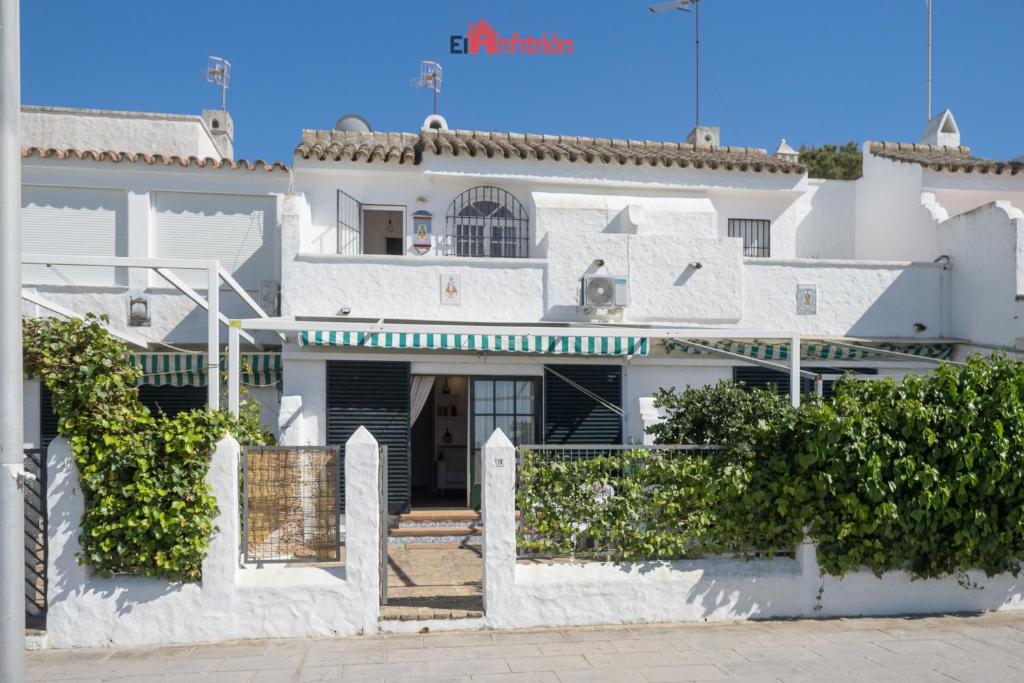 ein weißes Haus mit einem Tor davor in der Unterkunft El Anfitrión - Casa Dunas in Sanlúcar de Barrameda
