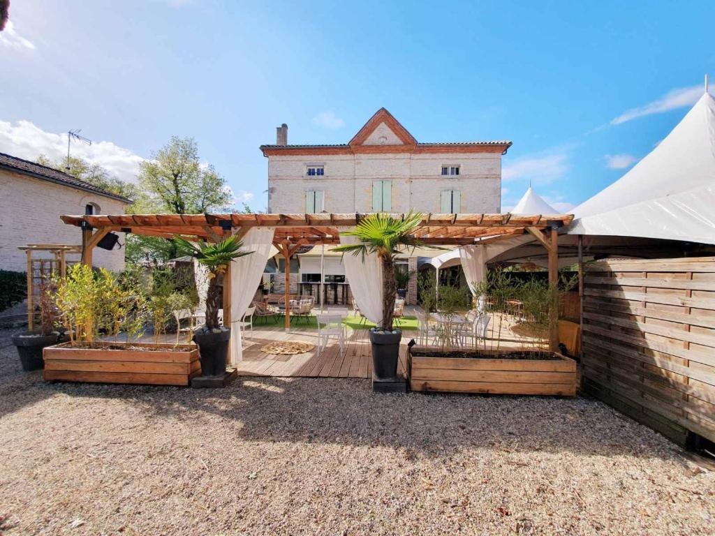 a pergola with palm trees in it in front of a building at Le Baraillot, Chambres et repas d'hôtes, soirée étape in Aiguillon