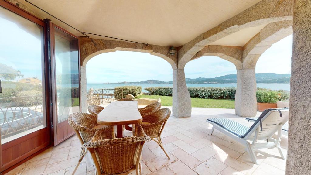 a patio with a table and chairs and a view of the water at Villetta Ginepri in Cannigione