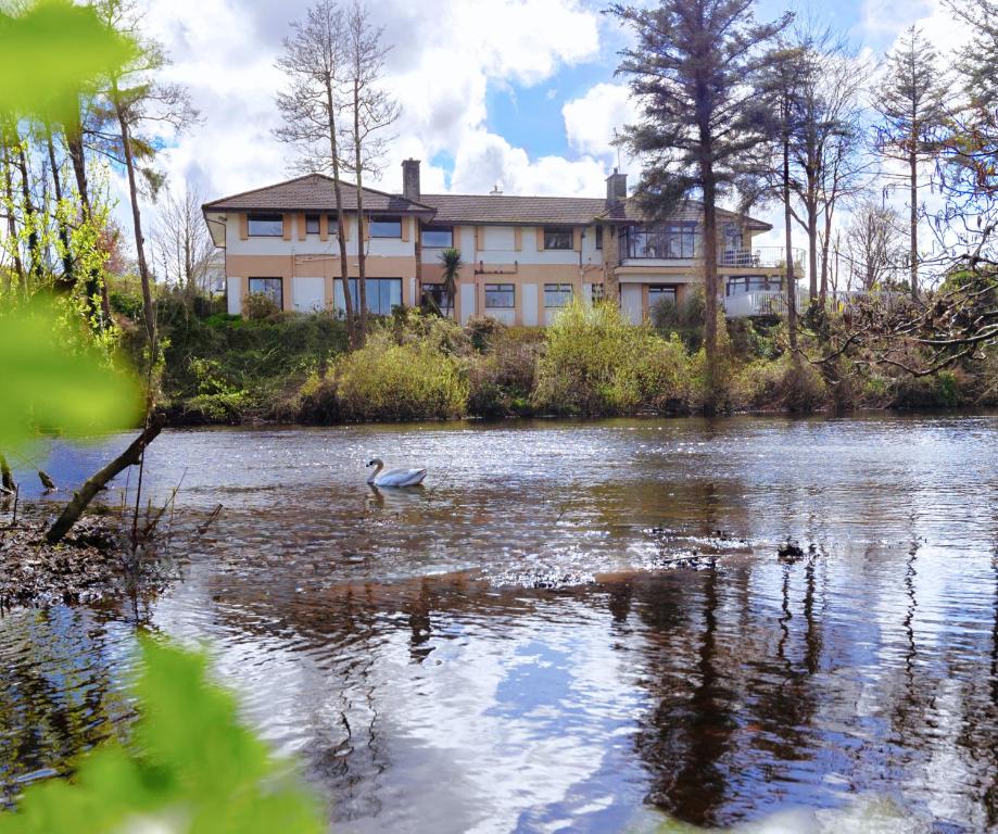 una casa grande a orillas de un lago con un pato en Killarney View House B&B, en Killarney