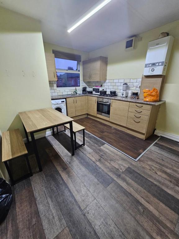 a large kitchen with a table and a bench in it at Double room with Shared Bathroom (3) in Manchester