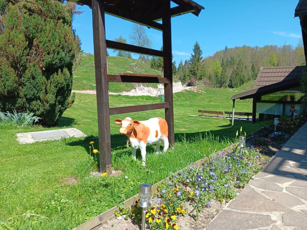 una vaca parada en el césped en un campo en turistična kmetija pr mark, en Trebče