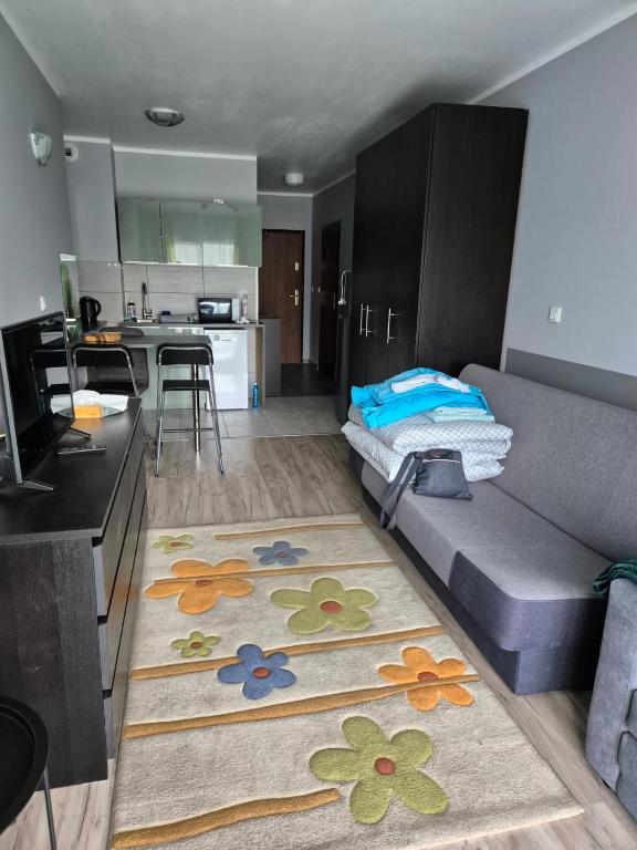 Una sala de estar con un sofá y una cocina. en Apartament Bunsha Kraków, en Cracovia