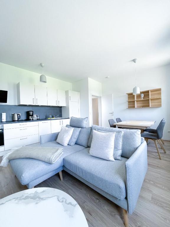 a living room with a blue couch and a kitchen at Ferienwohnung auf dem Hof Postma in Lambrechtshagen