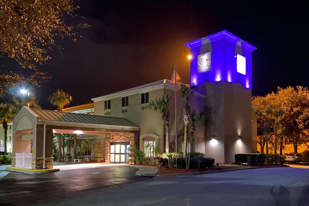 ein Gebäude mit einem Uhrturm mit violetten Lichtern in der Unterkunft Sleep Inn -Daytona Beach I-95 Exit 268 in Ormond Beach