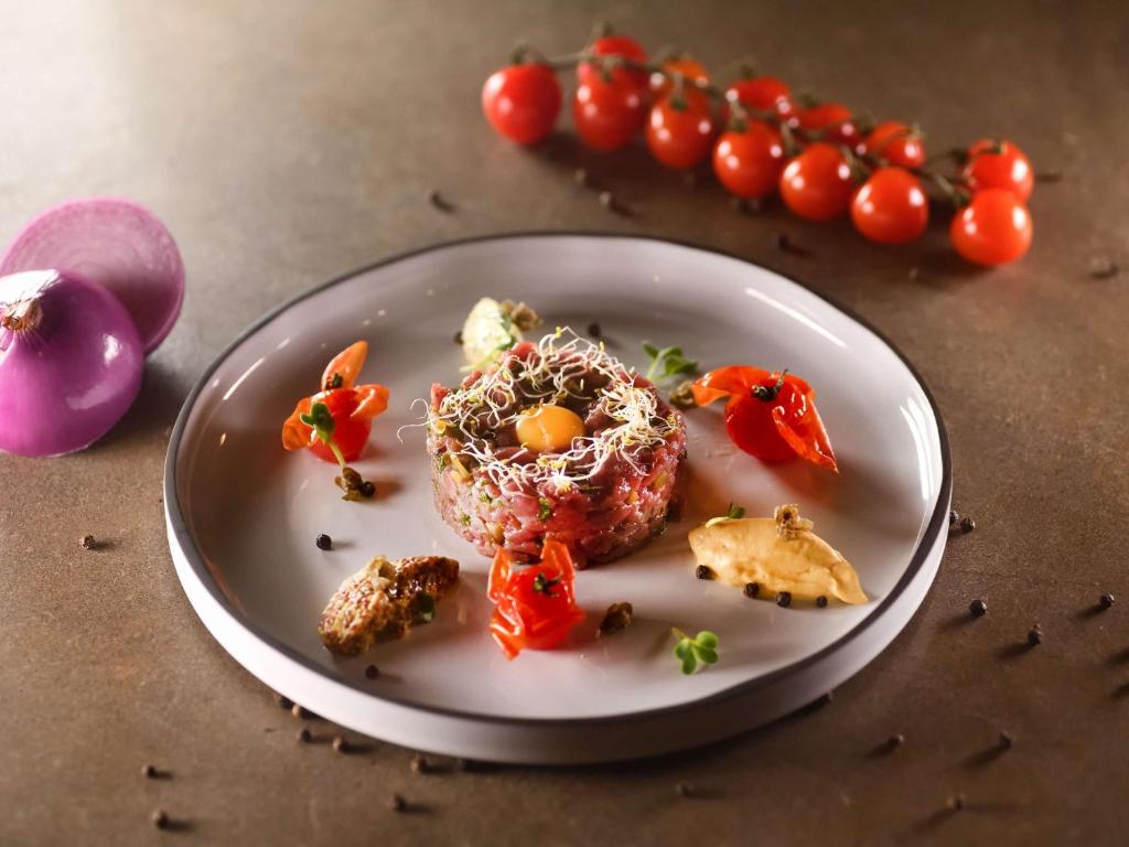 a plate of food with tomatoes on a table at Mövenpick Hotel Abidjan in Abidjan