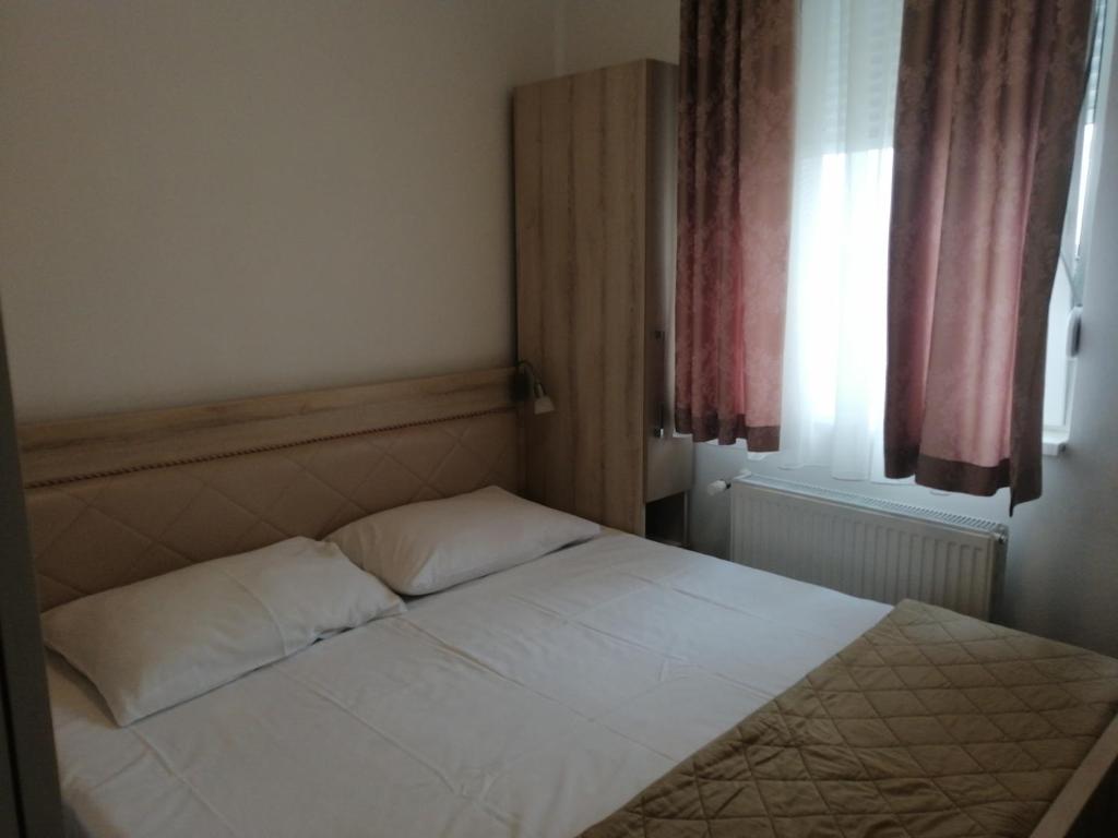 Schlafzimmer mit einem weißen Bett und einem Fenster in der Unterkunft Wing Apartman Jagodina in Jagodina
