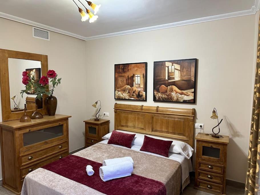 a bedroom with two beds and three paintings on the wall at Piso en Linares zona centro con parking gratis in Linares