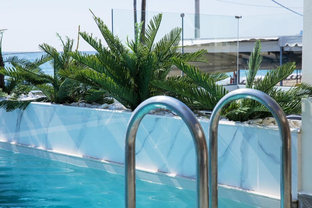a swimming pool with a fence and a palm tree at Agios Gordios Boutique Resort in Agios Gordios