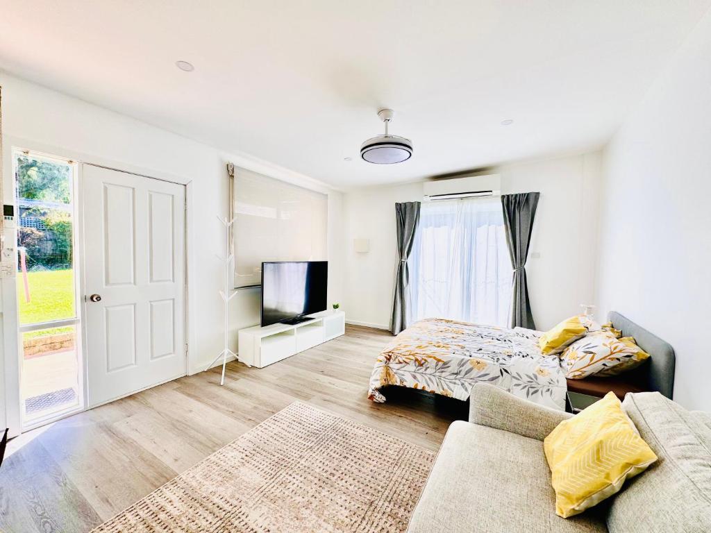 a bedroom with a couch and a bed and a tv at Modern Pod in the heart of Woden Valley in Lyons