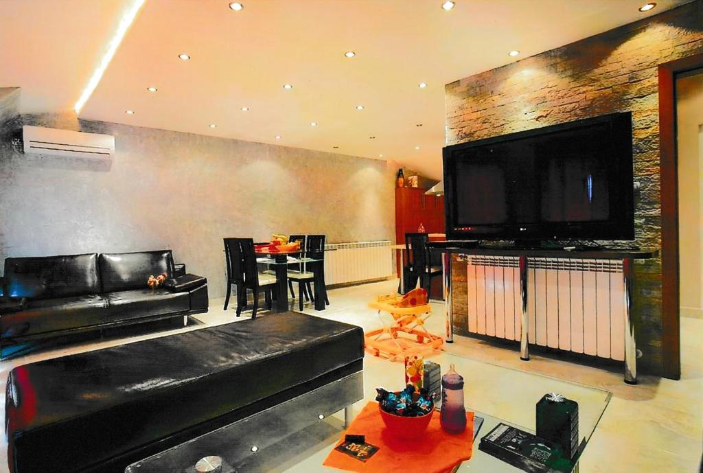 a living room with a black leather couch and a flat screen tv at Тристаен апартамент -УЮТ и Топлина in Yambol