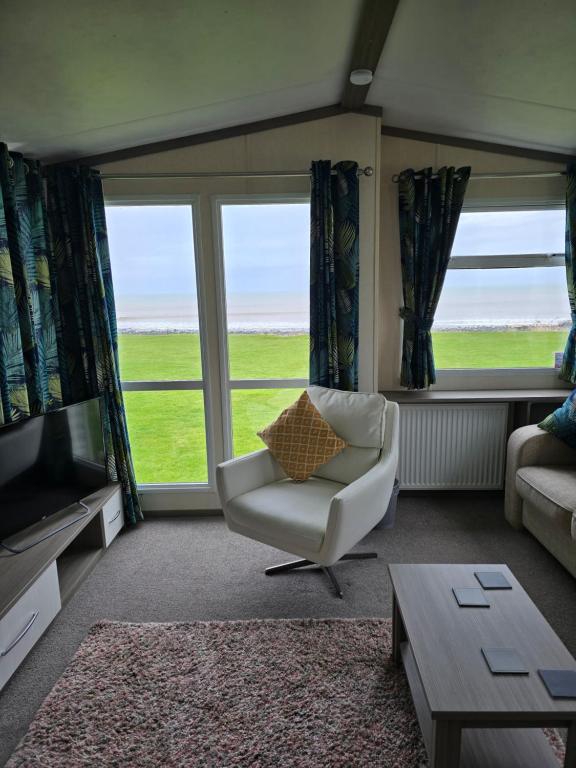 a living room with a couch and a chair and a television at Bayview at Pengarreg in Llanrhystyd