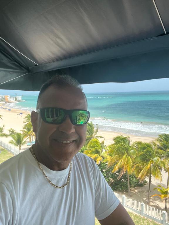 a man wearing sunglasses in front of a beach at Ismael in San Juan