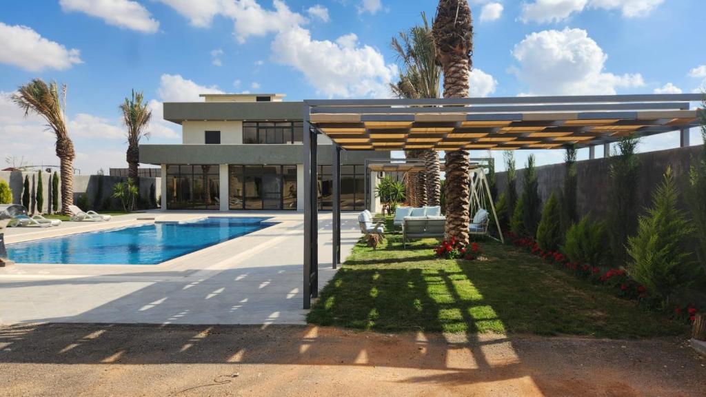 a house with a swimming pool and a wooden umbrella at ROSE in Umm el ‘Amad