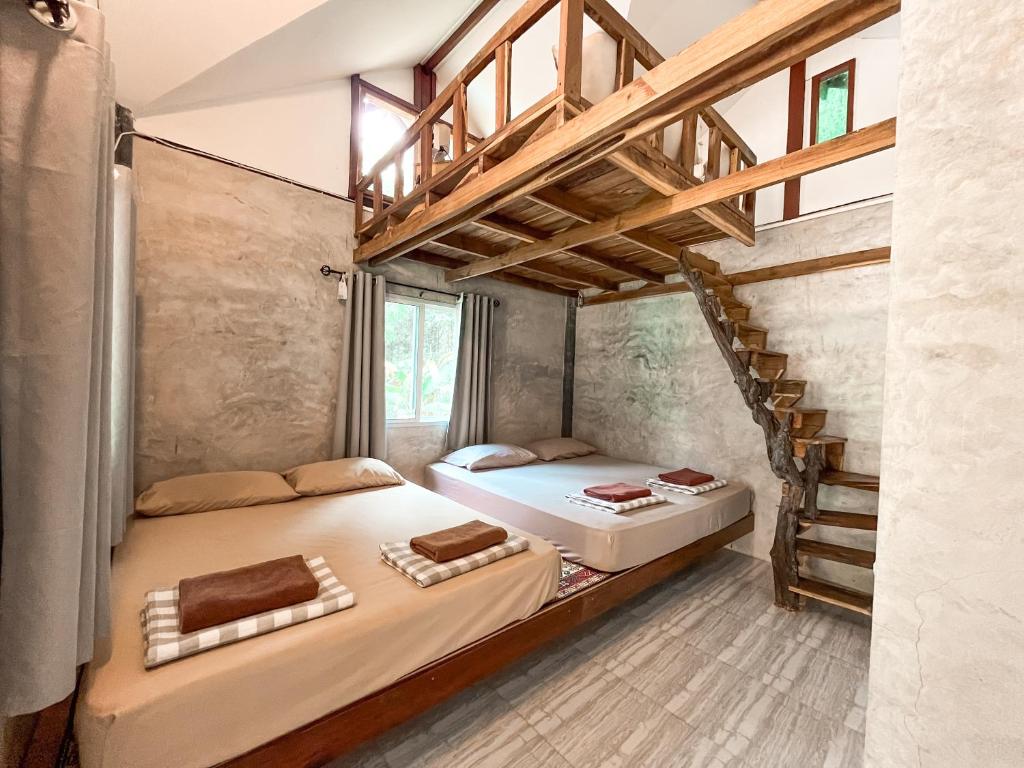 two beds in a room with a staircase at Eve house koh kood in Ko Kood