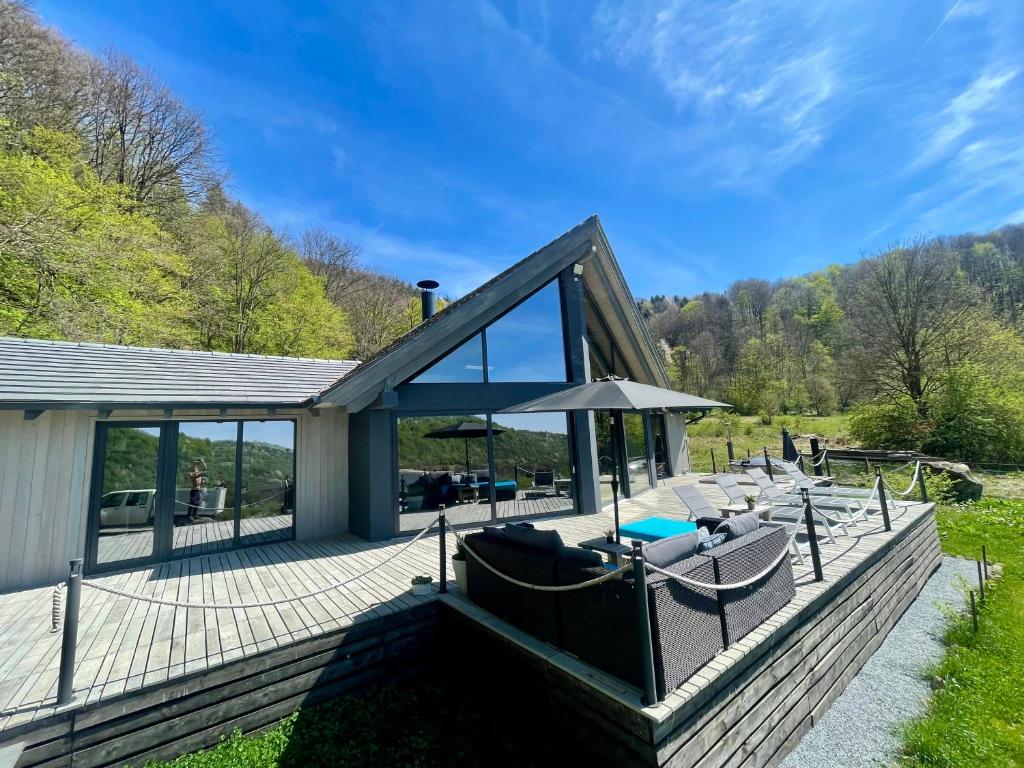 eine Holzterrasse mit Stühlen und einem Sonnenschirm in der Unterkunft KissHaz in Sovata